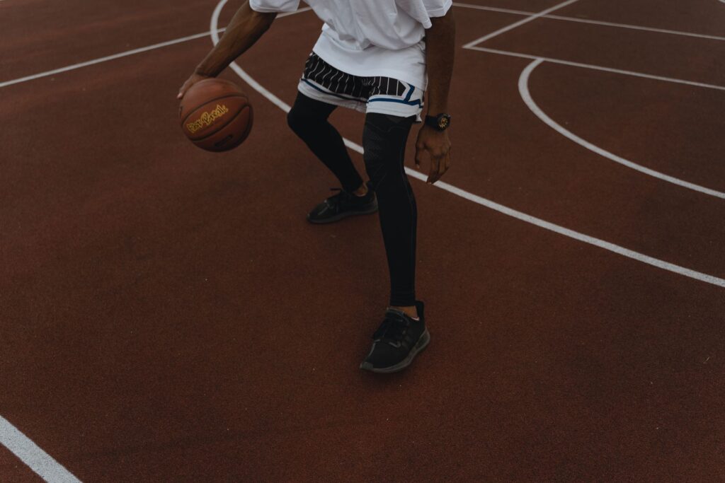 Mand der spiller basketball på en udendørs bane