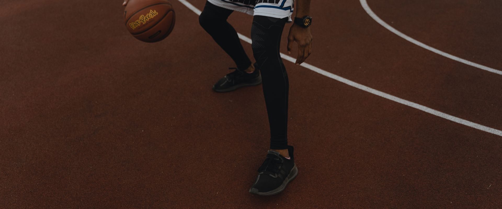 Mand der spiller basketball på en udendørs bane