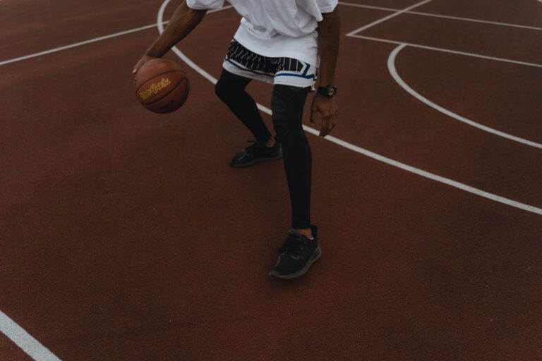 Mand der spiller basketball på en udendørs bane