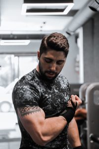 Muskuløs mand spænder biceps i fitnesscenter