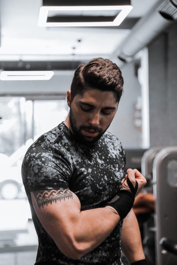 Muskuløs mand spænder biceps i fitnesscenter