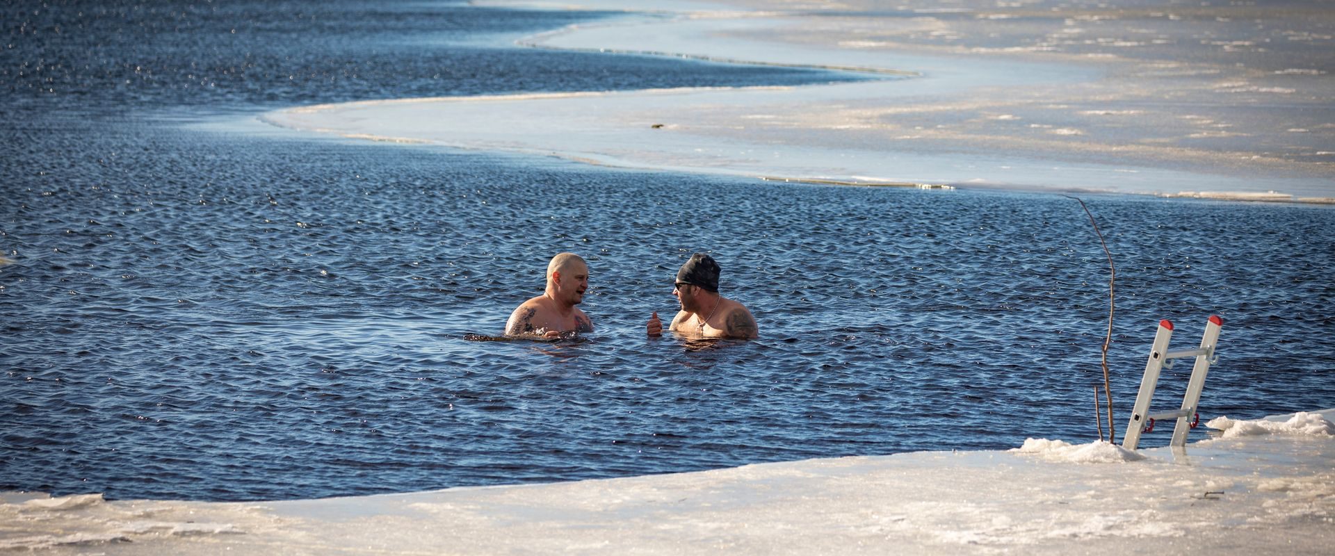 To mænd vinterbader i en frossen sø