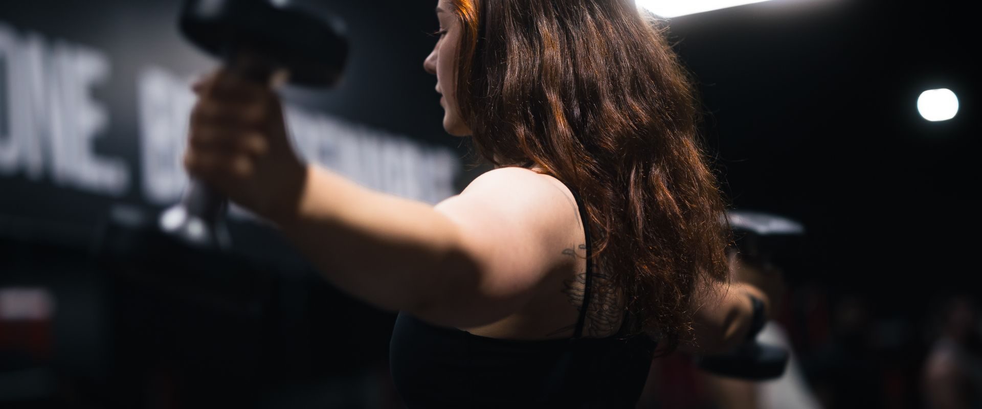 Kvinde træner med håndvægte i fitnesscenter