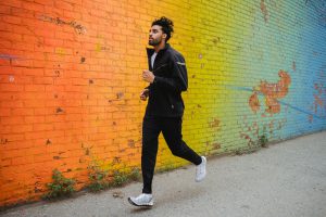 Ung mand løber forbi en graffitivæg