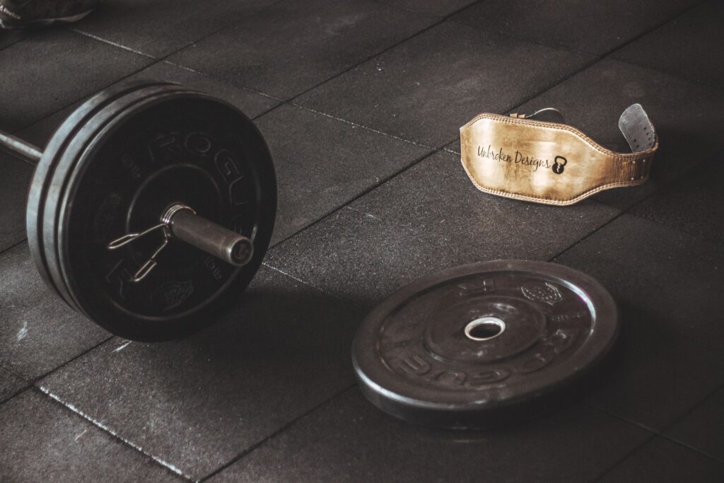 Vægtstang og løftebælte på gulvet i et fitnesscenter