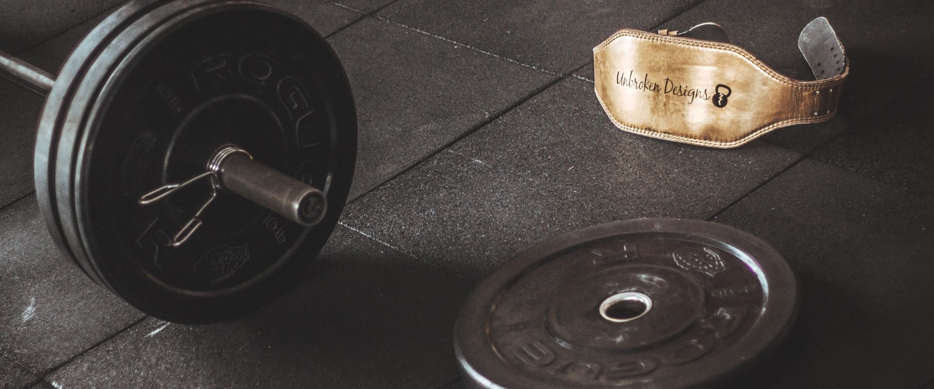 Vægtstang og løftebælte på gulvet i et fitnesscenter