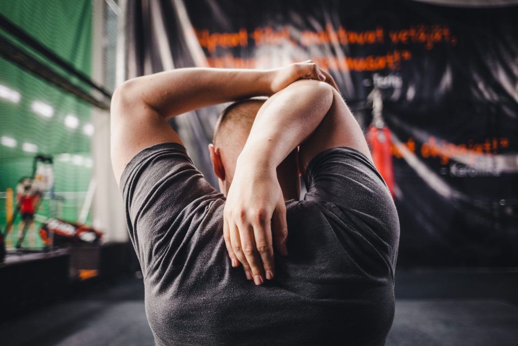 Mand strækker armene i fitnesscenter