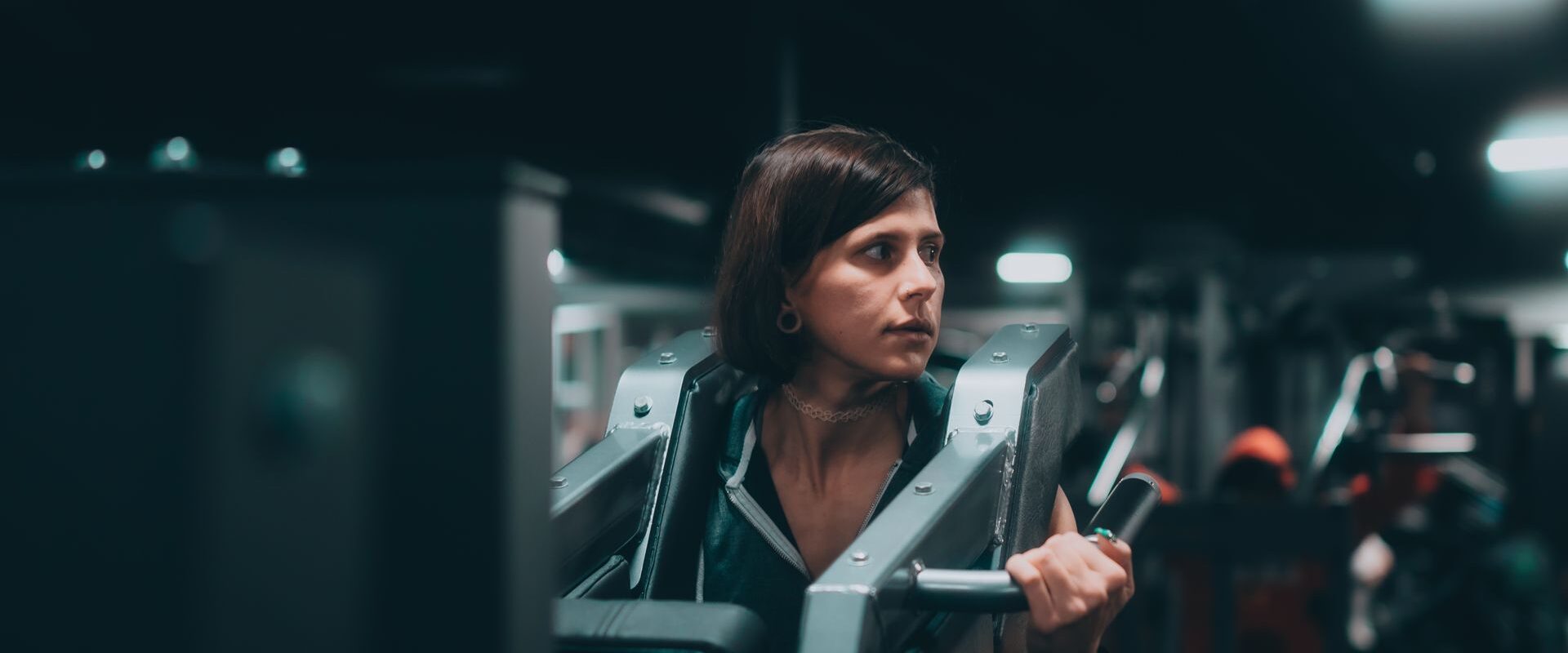 Fokuseret kvinde løfter vægte i fitnesscenter