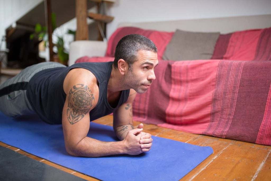 Mand laver planke på yogamåtte