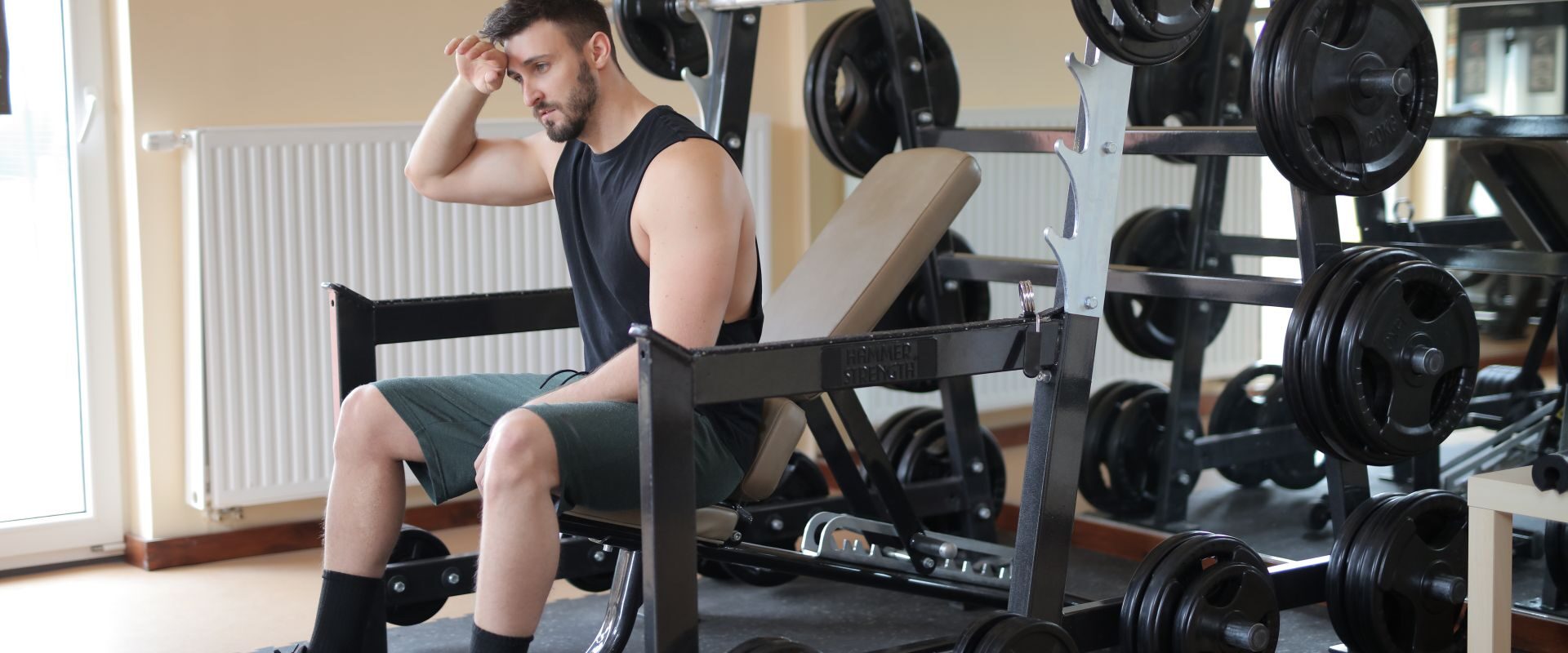 Mand sidder på en træningsbænk i fitnesscentret