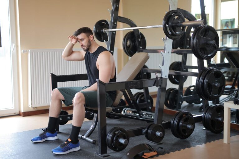 Mand sidder på en træningsbænk i fitnesscentret