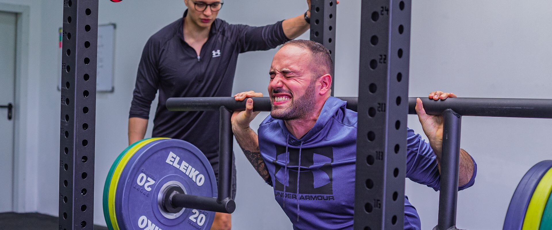 Mand træner med vægtstang i et fitnesscenter